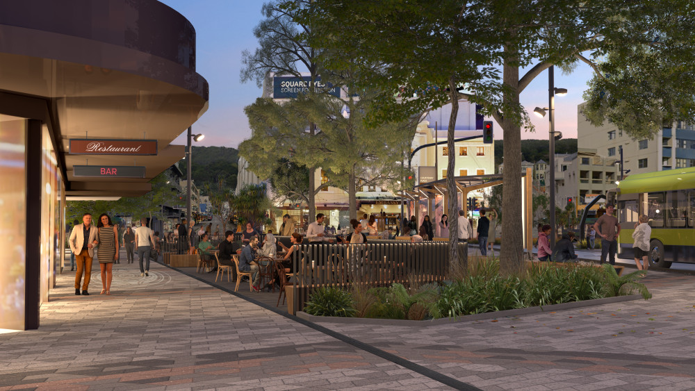 Image shows Courtenay place once construction is complete. The image is looking towards the Embassy Theatre, from the Northern side of the street. There is a wide footpath on the left, dining areas in the middle, new planting and trees. On the right you can see a bus stop. In the background you can see the Embassy Theatre. 