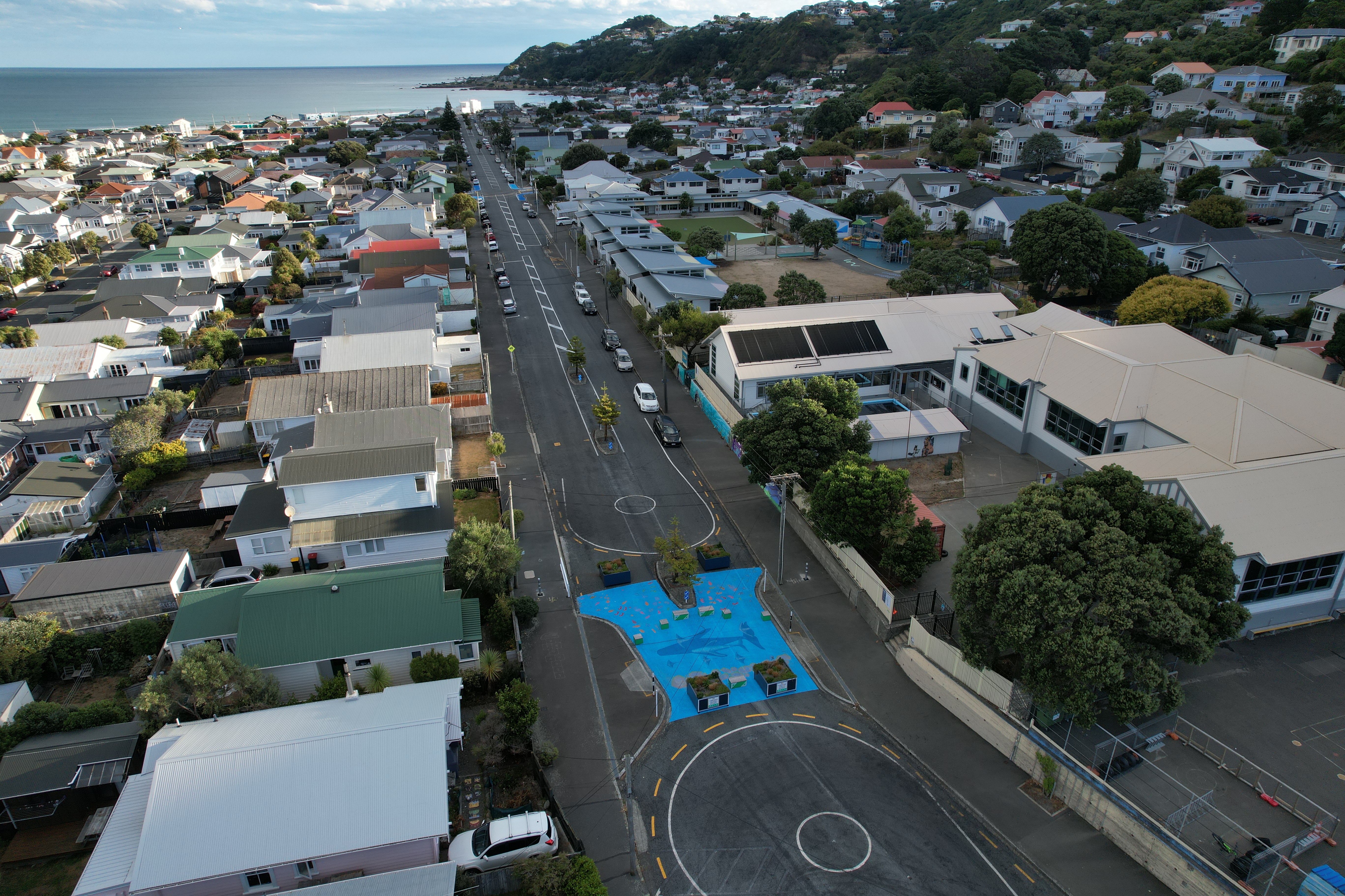 Birds eye view of street closure with big blue sea mural painted on the road and planter boxes.